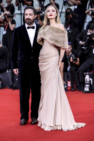 Angelina Jolie attended the premiere of her upcoming film 'Maria' at the Venice Film Festival in a faux-fur shrug gown. See her full look, here.