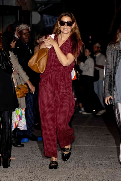 Look of the Day for August 23, 2024 features Katie Holmes in a raspberry colored jumpsuit, oversized sunglasses, pearl necklace, and buckled ballet flats. Shop her look from brands like Miu Miu, Ganni, and Steve Madden,