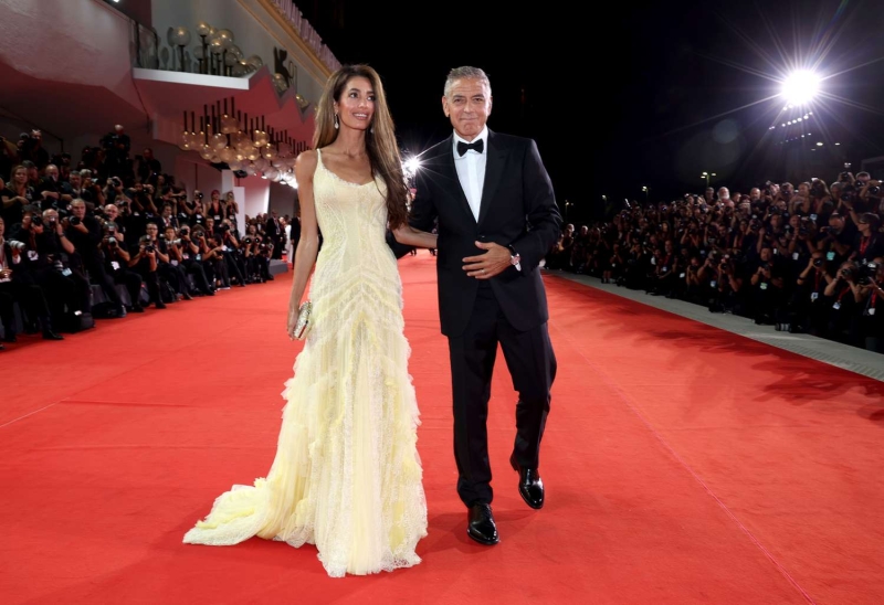 Amal Clooney stepped out in another stylish and colorful outfit at the Venice Film Festival, wearing a bright tangerine jumpsuit with George Clooney on Tuesday, Sept. 3.