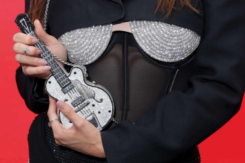 Ashley Park put her own spin on the method dressing trend by doing it with her accessories. She channeled her 'Emily in Paris' character, Mindy, with a teeny tiny sparkly guitar purse.