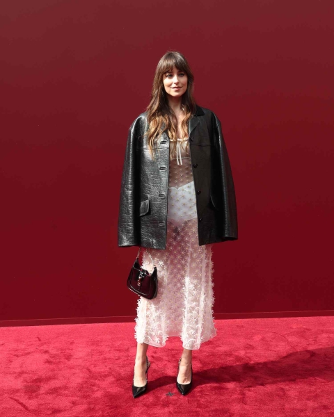 Dakota Johnson wore a sheer white boho midi dress paired with a cracked black leather jacket to the Gucci Women's Spring Summer 2025 Fashion Show during the Milan Fashion Week.