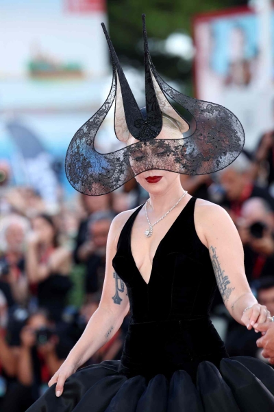 Lady Gaga appeared at Venice Film Festival wearing a giant black ballgown with a petal-like hoop skirt and a plunging neckline along with a towering black lace headpiece. The event marked her red carpet debut with fiancé Michael Polansky.