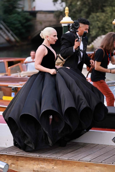 Lady Gaga appeared at Venice Film Festival wearing a giant black ballgown with a petal-like hoop skirt and a plunging neckline along with a towering black lace headpiece. The event marked her red carpet debut with fiancé Michael Polansky.