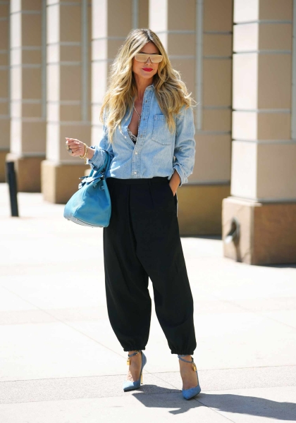 Look of the Day for September 4, 2024 features Heidi Klum in black parachute pants, a denim button-down shirt, denim heels, and gold shield sunglasses while out in California.