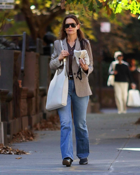 Look of the Day for October 28, 2024 features Katie Holmes wearing a taupe blazer and chocolate brown shirt with light-wash straight jeans and black boots.