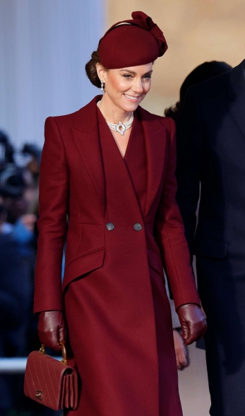 Kate Middleton arrived at her annual Christmas Carol concert wearing a floor length red pea coat that feature a large, black velvet bow at the neckline. She accessorized with velvet black boots.