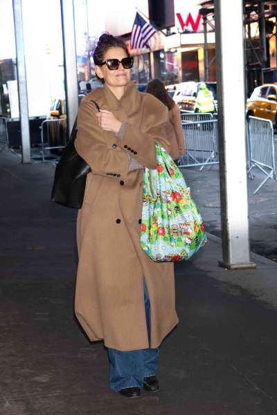 Katie Holmes was spotted in New York City wearing a look that was equal parts chic and practical, pairing a stylish brown maxi wool coat with a Hello Kitty tote bag.