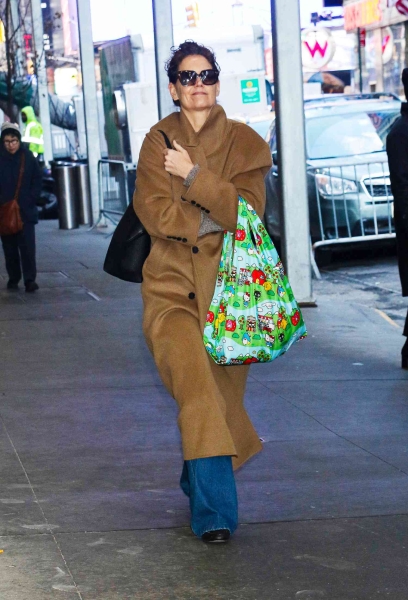 Katie Holmes was spotted in New York City wearing a look that was equal parts chic and practical, pairing a stylish brown maxi wool coat with a Hello Kitty tote bag.