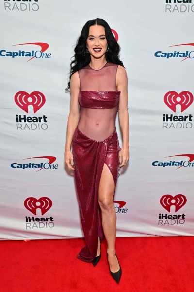 Katy Perry put her entire stomach on display in a sheer burgundy sequin gown with mesh panels while posing on the red carpet at the 2024 Jingle Ball concert.