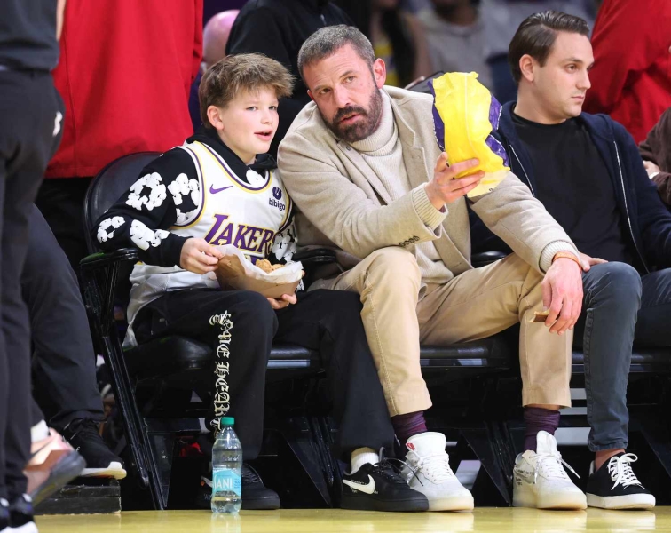 Ben Affleck and his lookalike youngest son Samuel had a matching style moment as they showed off similar versions of the same ultra-rare footwear at the February 6 Lakers and Warriors basketball game. See their complementary father-son looks, here.